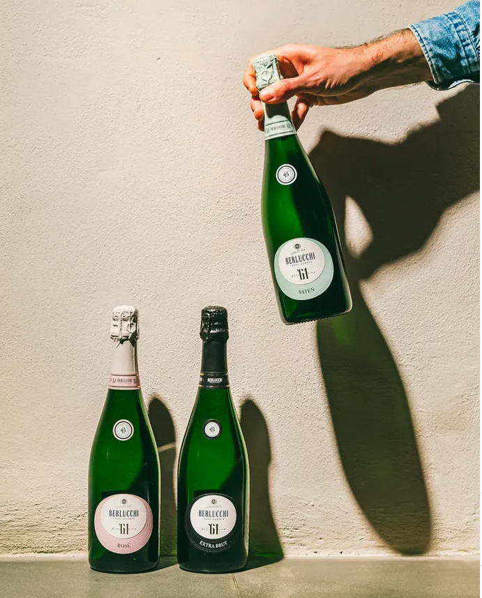 3 verschiedene Berlucchi Flaschen vor Wand werfen Schatten