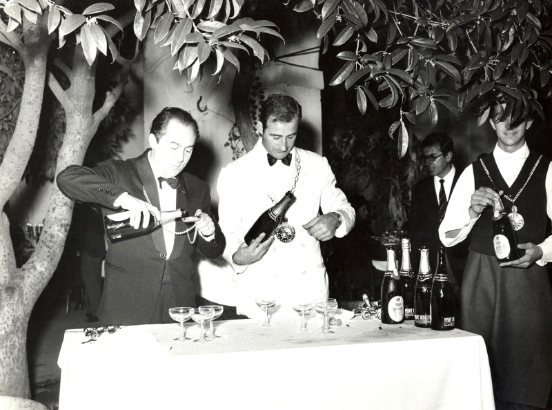 Männer in Anzügen schenken Franciacorta in Sektschalen