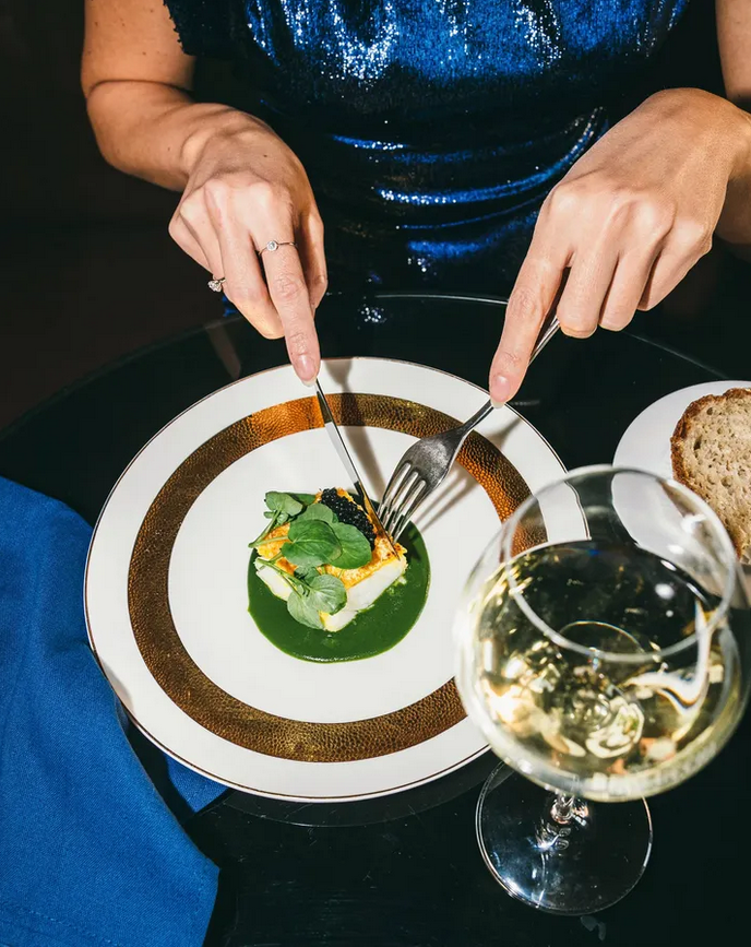 Frau vor Teller mit Vorspeise und Glas Franciacorta