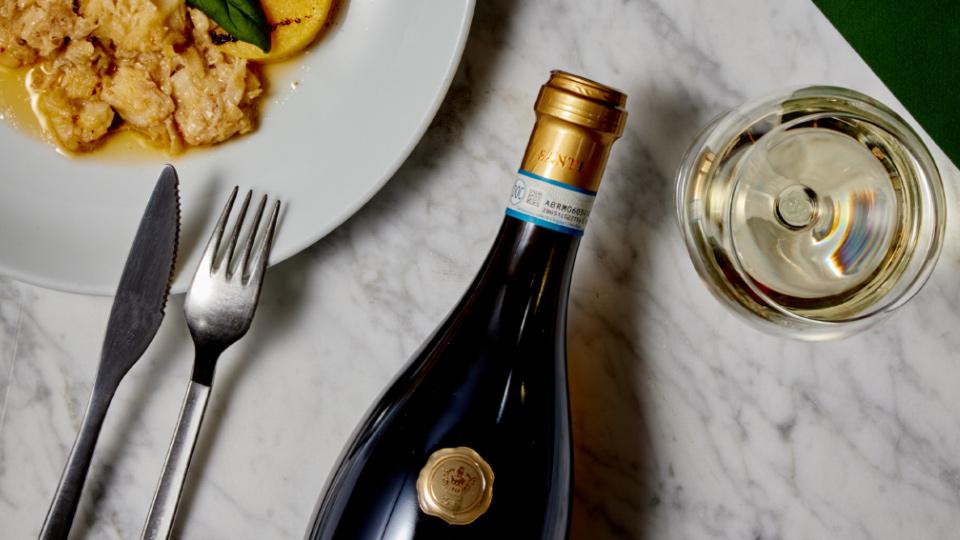 Santi Folar Lugana neben Teller mit Speise