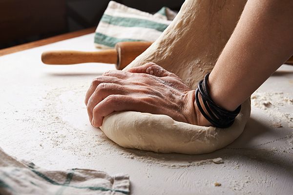 Pizzateig wird mit Händen geknetet